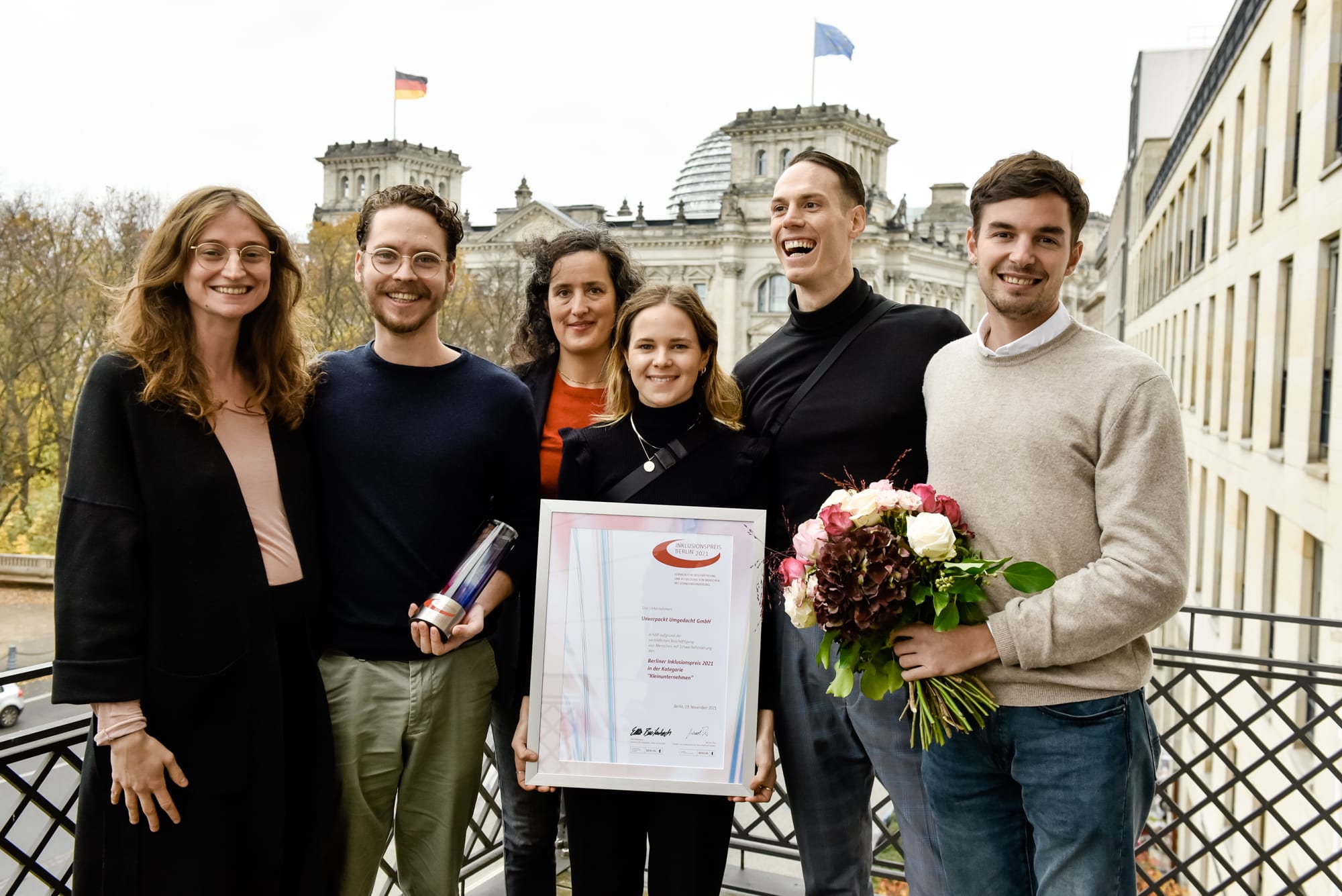 3 mitarbeiterinnen & 3 mitarbeiter mit blumen, zertifikat und inklusionspreis in berlin